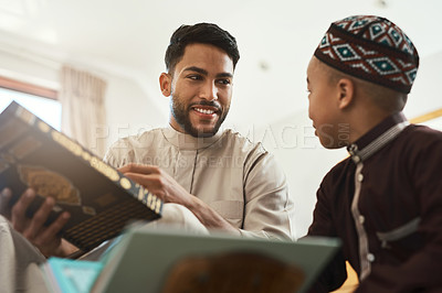 Buy stock photo Shot of a young muslim man and his son reading in the lounge at home