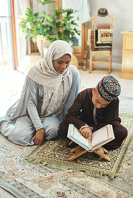 Buy stock photo Shot of a young muslim mother and her son reading in the lounge at home