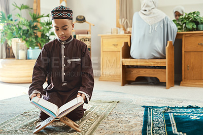 Buy stock photo Shot of a young muslim boy reading in the lounge at home