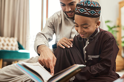 Buy stock photo Shot of a young muslim man and his son reading in the lounge at home