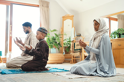 Buy stock photo Shot of a young muslim couple and their son praying in the lounge at home