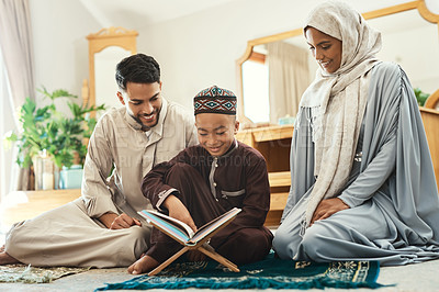 Buy stock photo Shot of a young muslim couple and their son reading in the lounge at home
