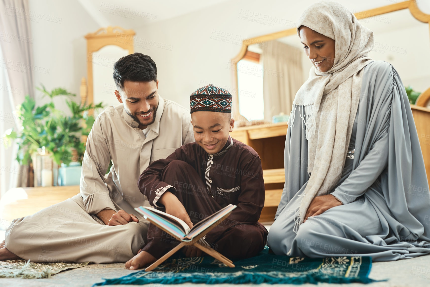 Buy stock photo Shot of a young muslim couple and their son reading in the lounge at home