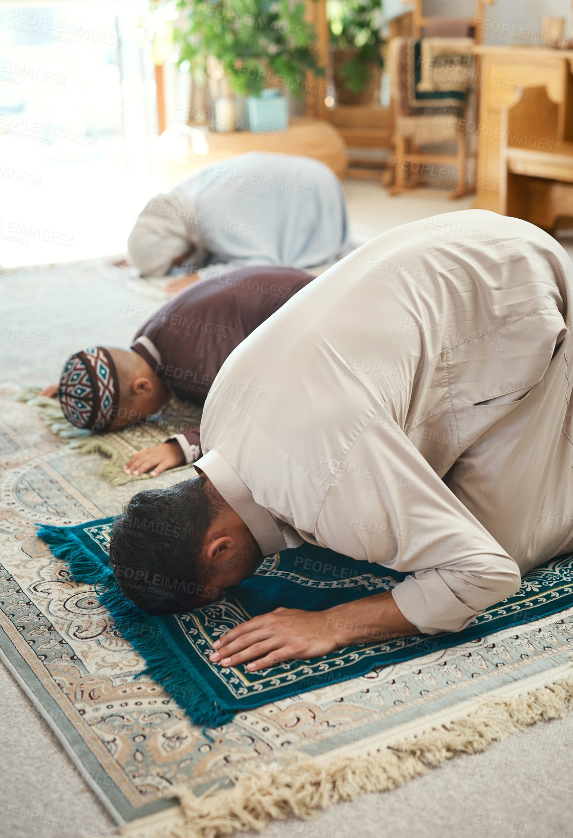 Buy stock photo Shot of a young muslim couple and their son praying in the lounge at home