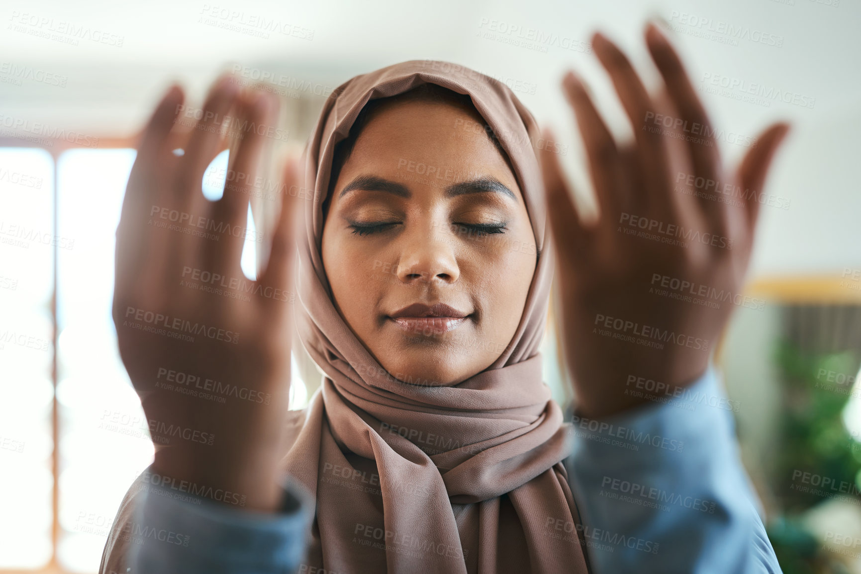Buy stock photo Shot of a young muslim woman praying in the lounge at home