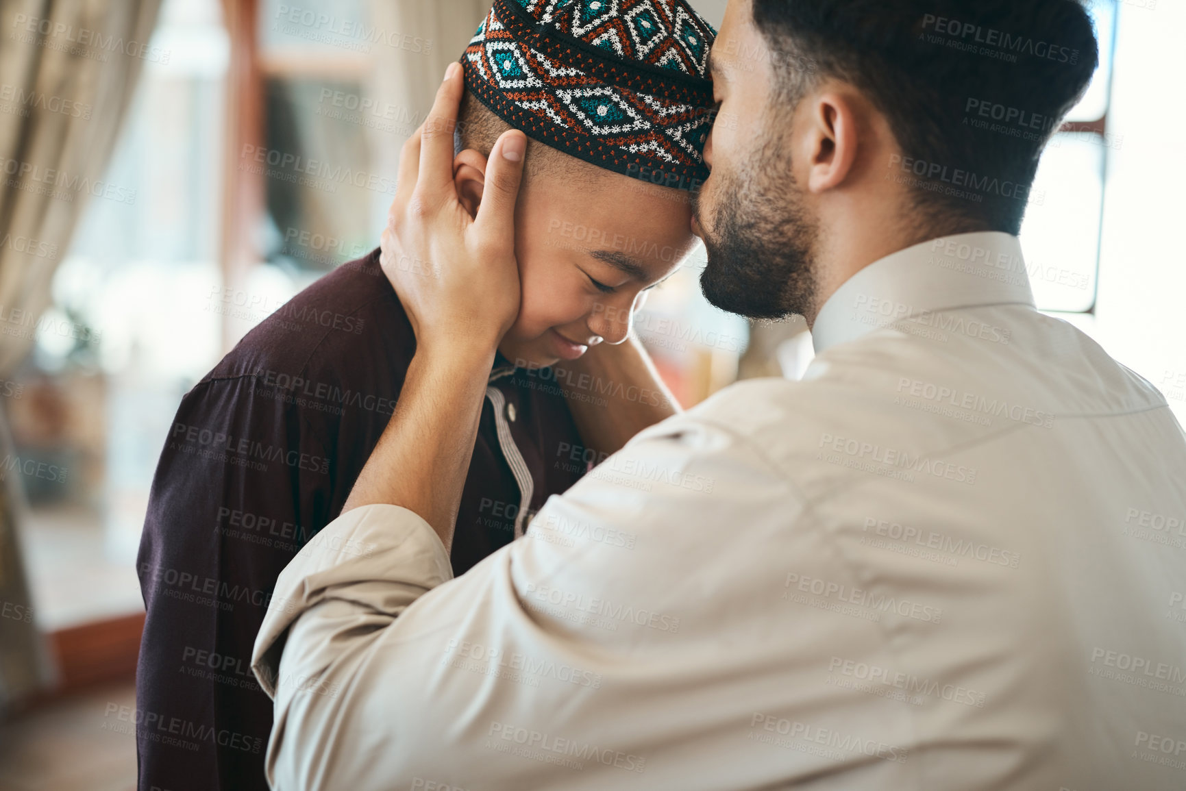 Buy stock photo Muslim father, parent or man kissing his son on the forehead, bonding and showing affection at home. Happy, smiling and Arab boy embracing, celebrating traditional holiday and being peaceful with dad