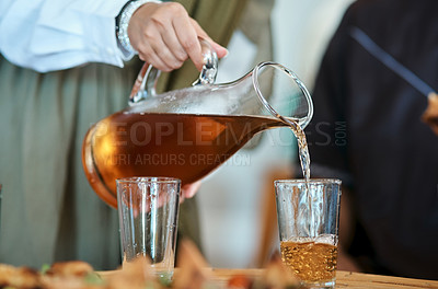 Buy stock photo Shot of a woman pouring a drink into glasses