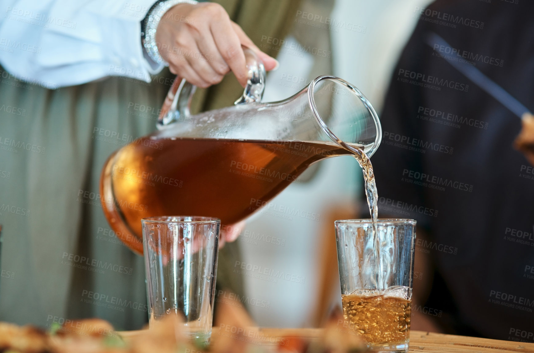 Buy stock photo Shot of a woman pouring a drink into glasses