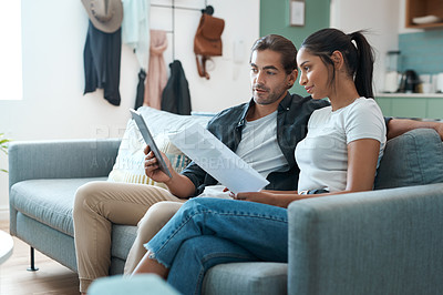 Buy stock photo Shot of a young couple doing paperwork while using a digital tablet at home