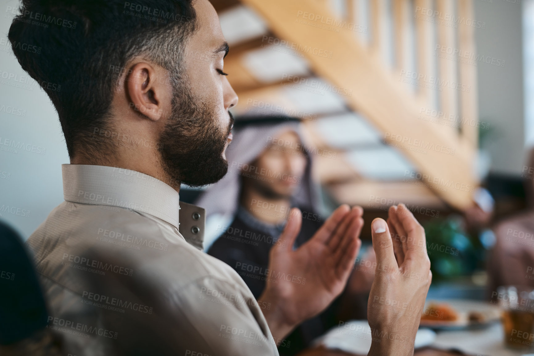 Buy stock photo Muslim, praying and religion while sitting with family and say a dua or prayer before breaking fast during the holy month of Ramadan. Religious man lifting his hands to pray during eid or iftar meal