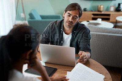 Buy stock photo Shot of a young couple doing paperwork while using a laptop at home