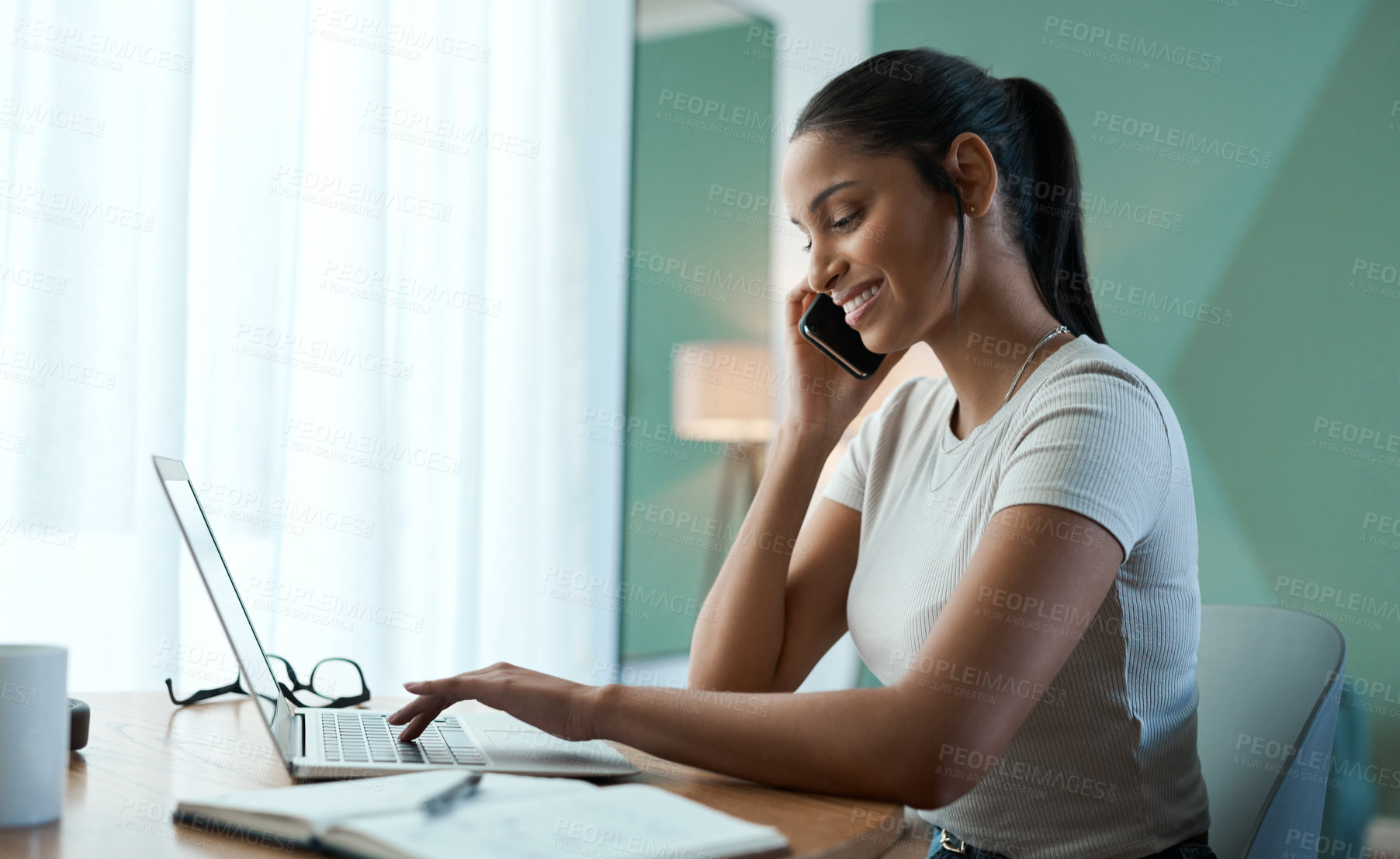 Buy stock photo Shot of a young woman doing paperwork while using a laptop at home