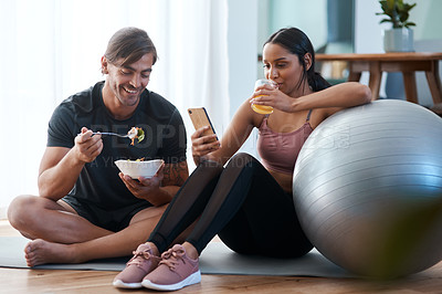 Buy stock photo Full length shot of an athletic young couple enjoying some healthy snacks after their workout at home