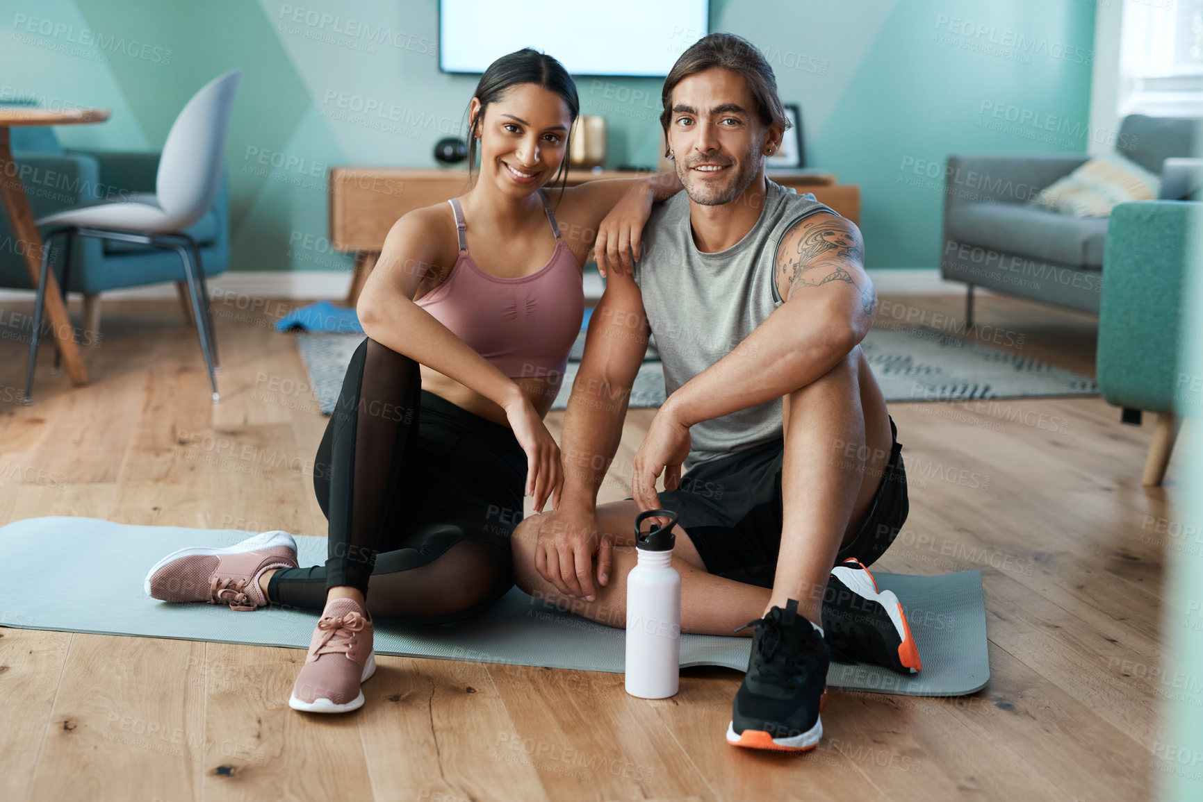 Buy stock photo Full length portrait of an athletic young couple sitting on an exercise mat during their workout at home