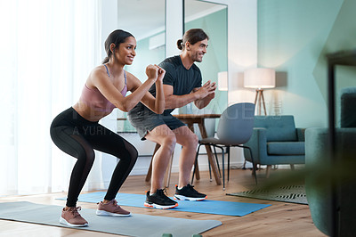 Buy stock photo Full length shot of an athletic young couple squatting on an exercise mat during their workout at home