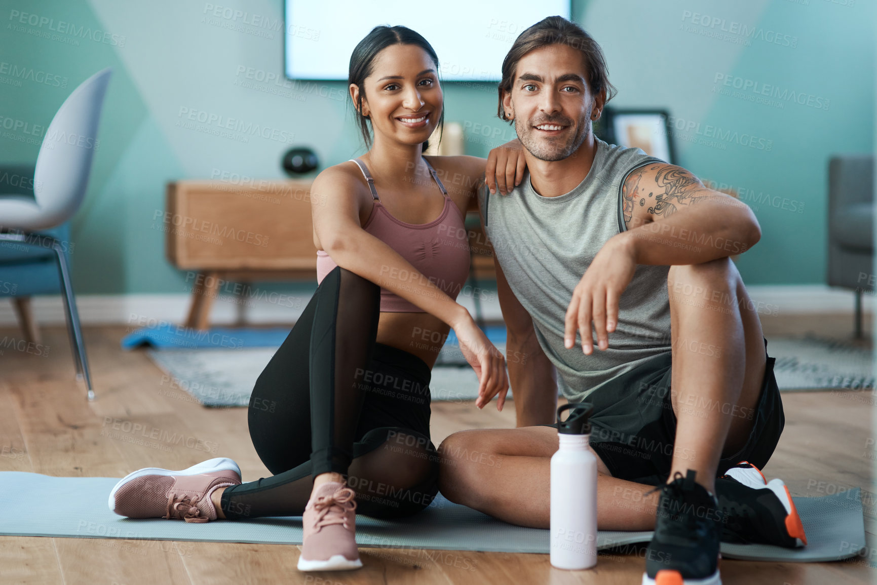 Buy stock photo Full length portrait of an athletic young couple sitting on an exercise mat during their workout at home