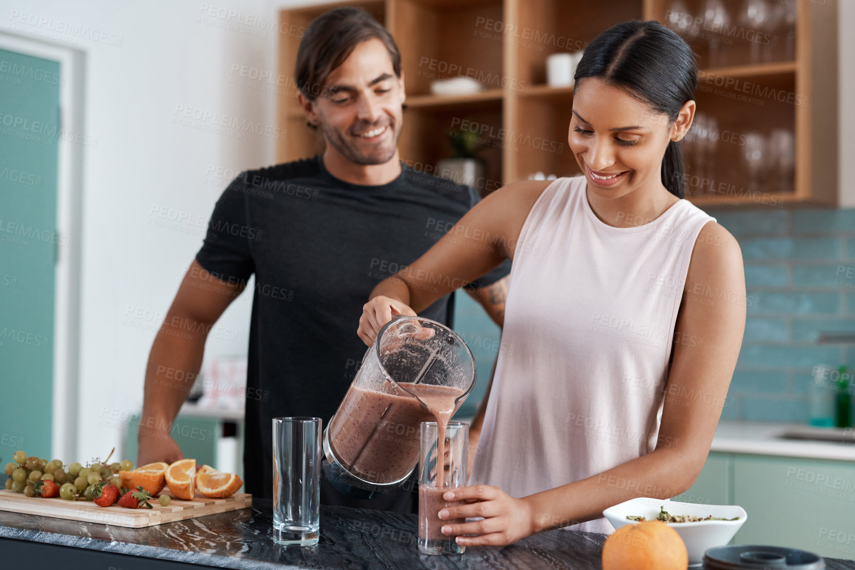 Buy stock photo Cropped shot of an affectionate young couple making smoothies in their kitchen at home