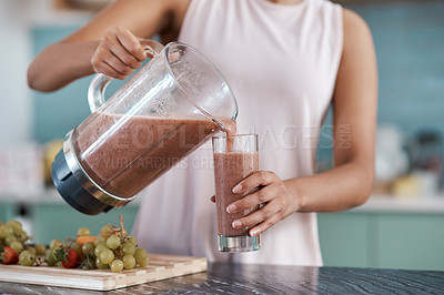 Buy stock photo Cropped shot of an unrecognizable young woman making smoothies in her kitchen at home