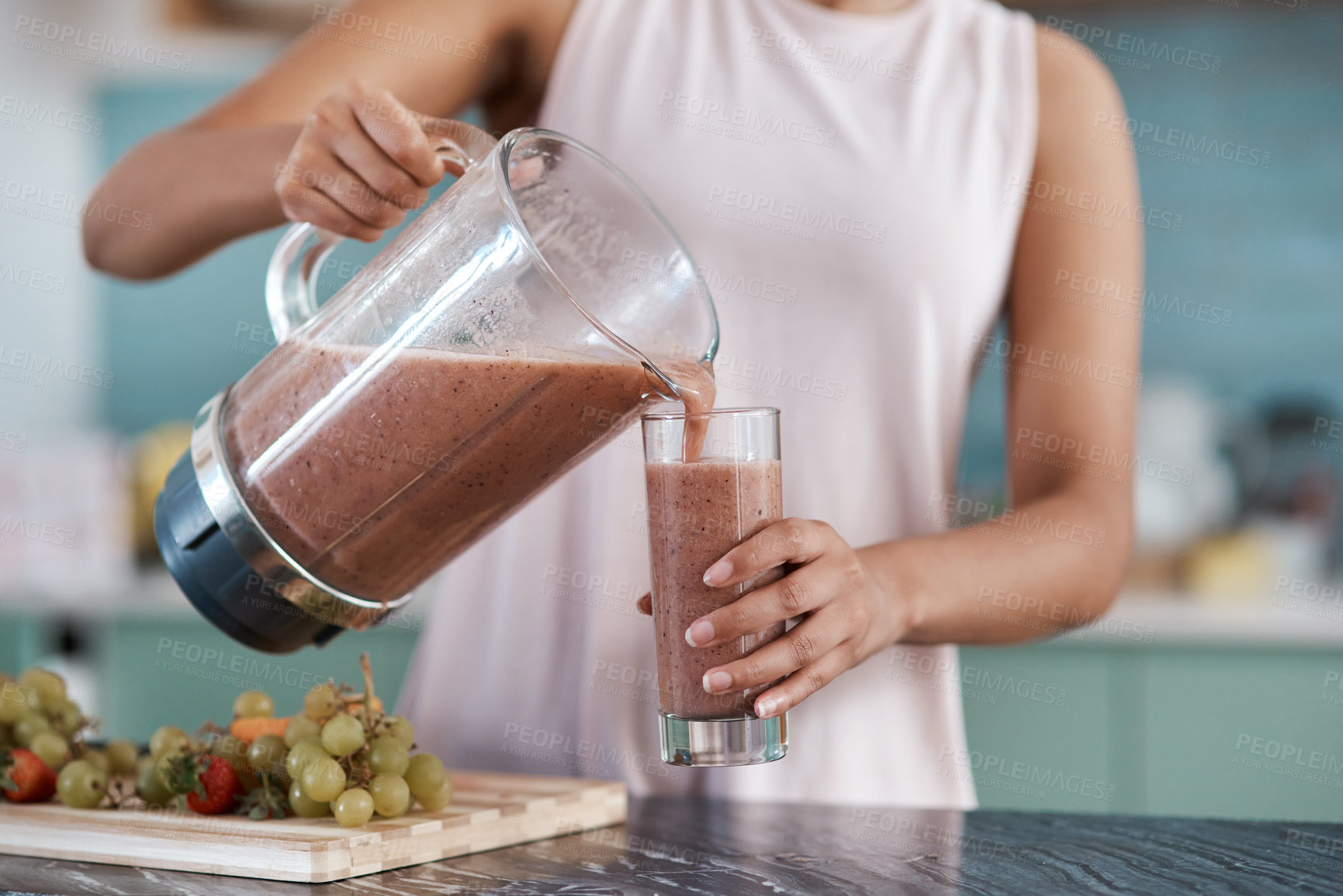 Buy stock photo Cropped shot of an unrecognizable young woman making smoothies in her kitchen at home