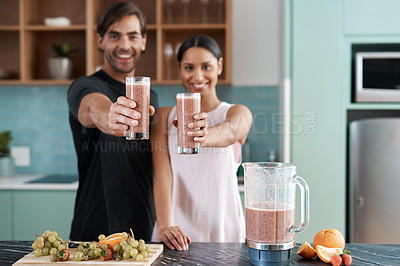 Buy stock photo Cropped portrait of an affectionate young couple making smoothies in their kitchen at home