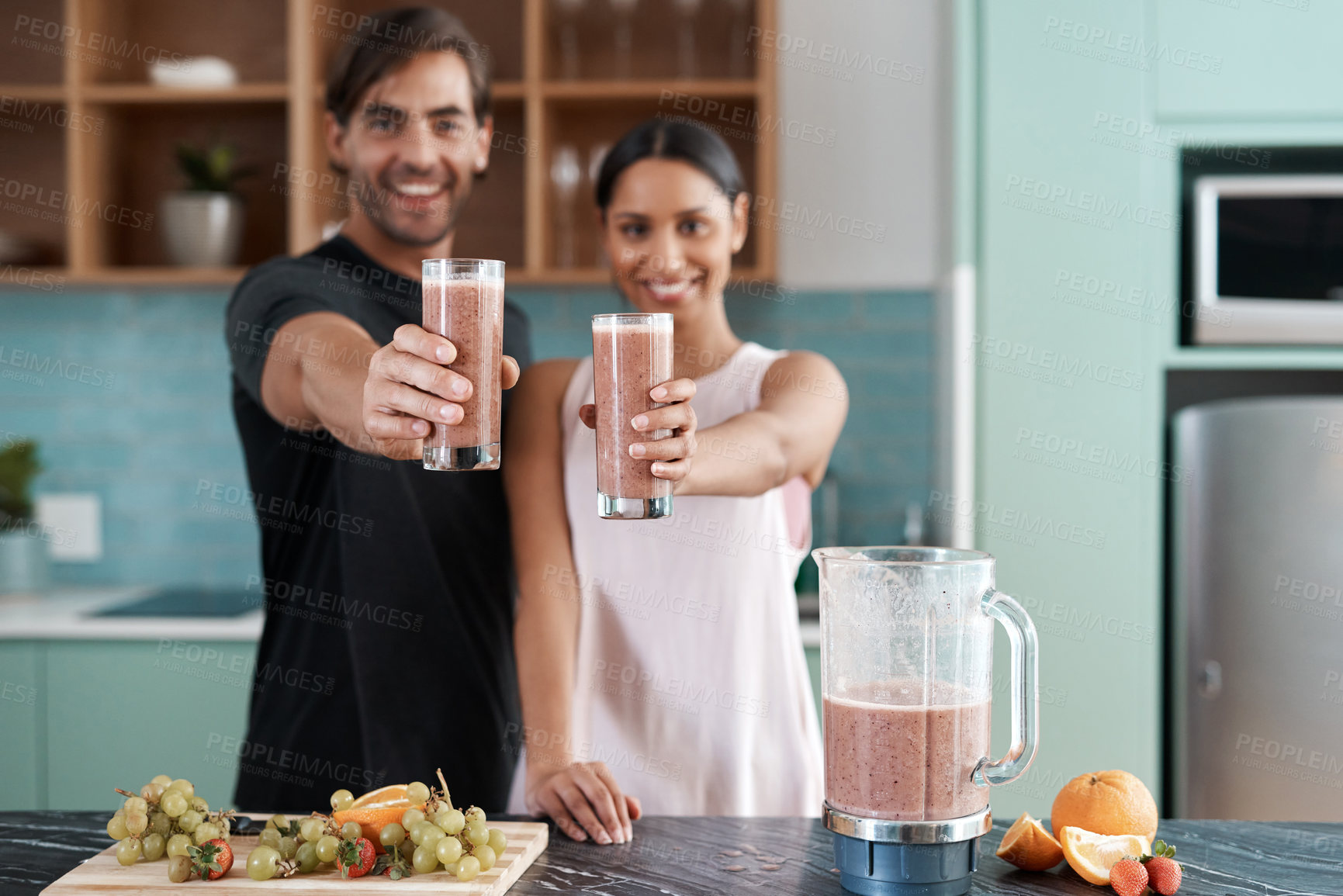 Buy stock photo Cropped portrait of an affectionate young couple making smoothies in their kitchen at home
