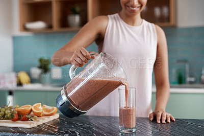 Buy stock photo Cropped shot of an unrecognizable young woman making smoothies in her kitchen at home