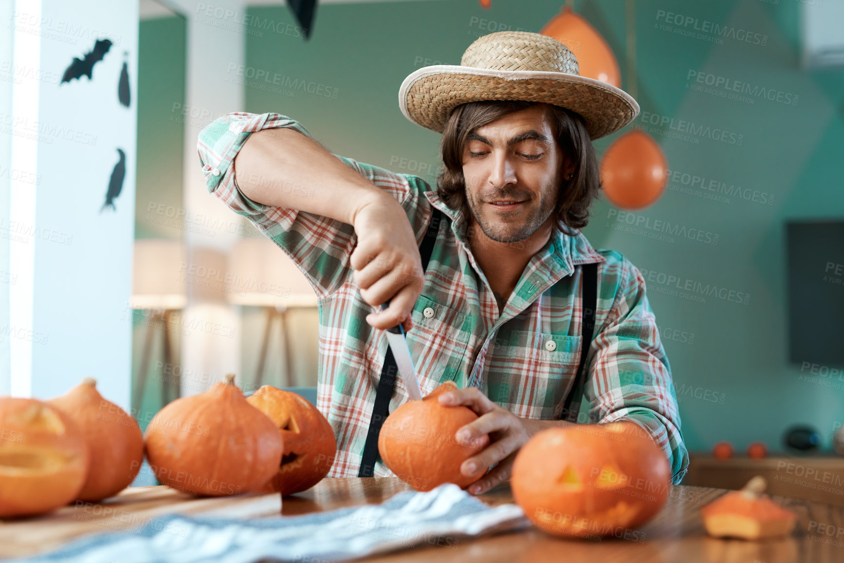 Buy stock photo Shot of a young man carving a pumpkin at home