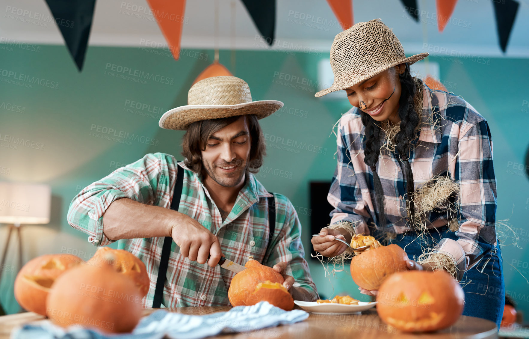 Buy stock photo Shot of a young couple carving pumpkins at home