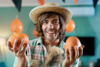 Buy stock photo Shot of a young man holding two pumpkins at home