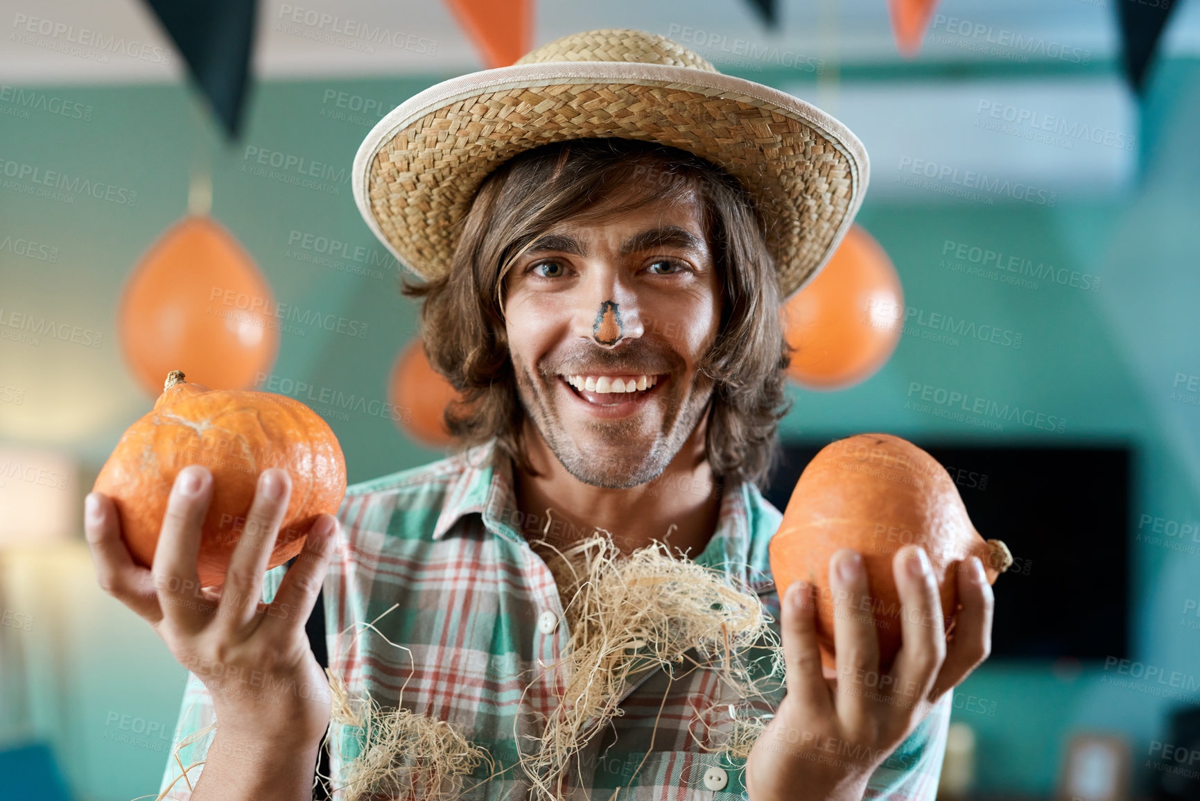 Buy stock photo Shot of a young man holding two pumpkins at home