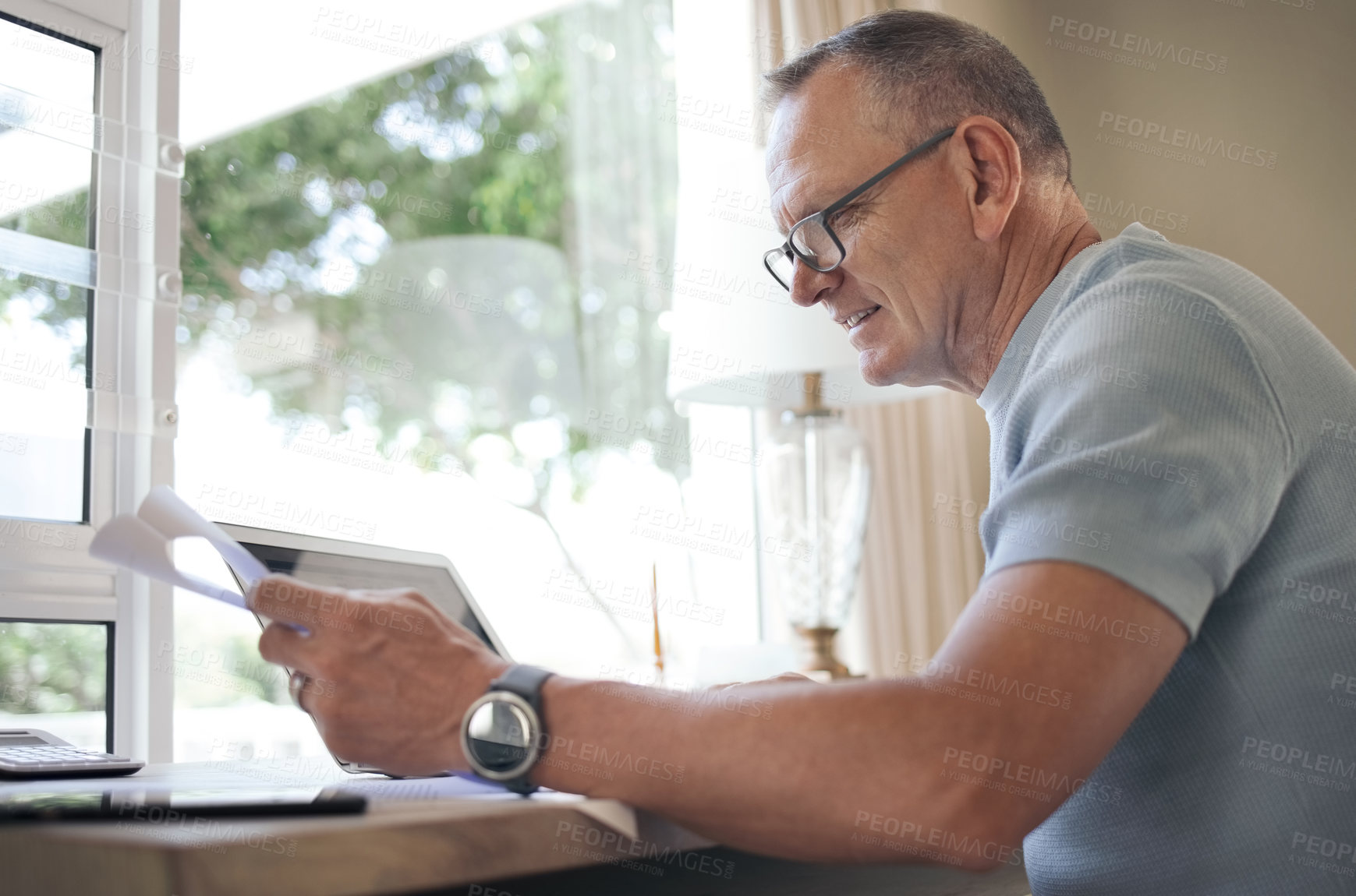 Buy stock photo Shot of a mature man reading over financial documents while working