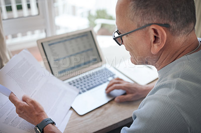 Buy stock photo Shot of a mature man reading over financial documents while working