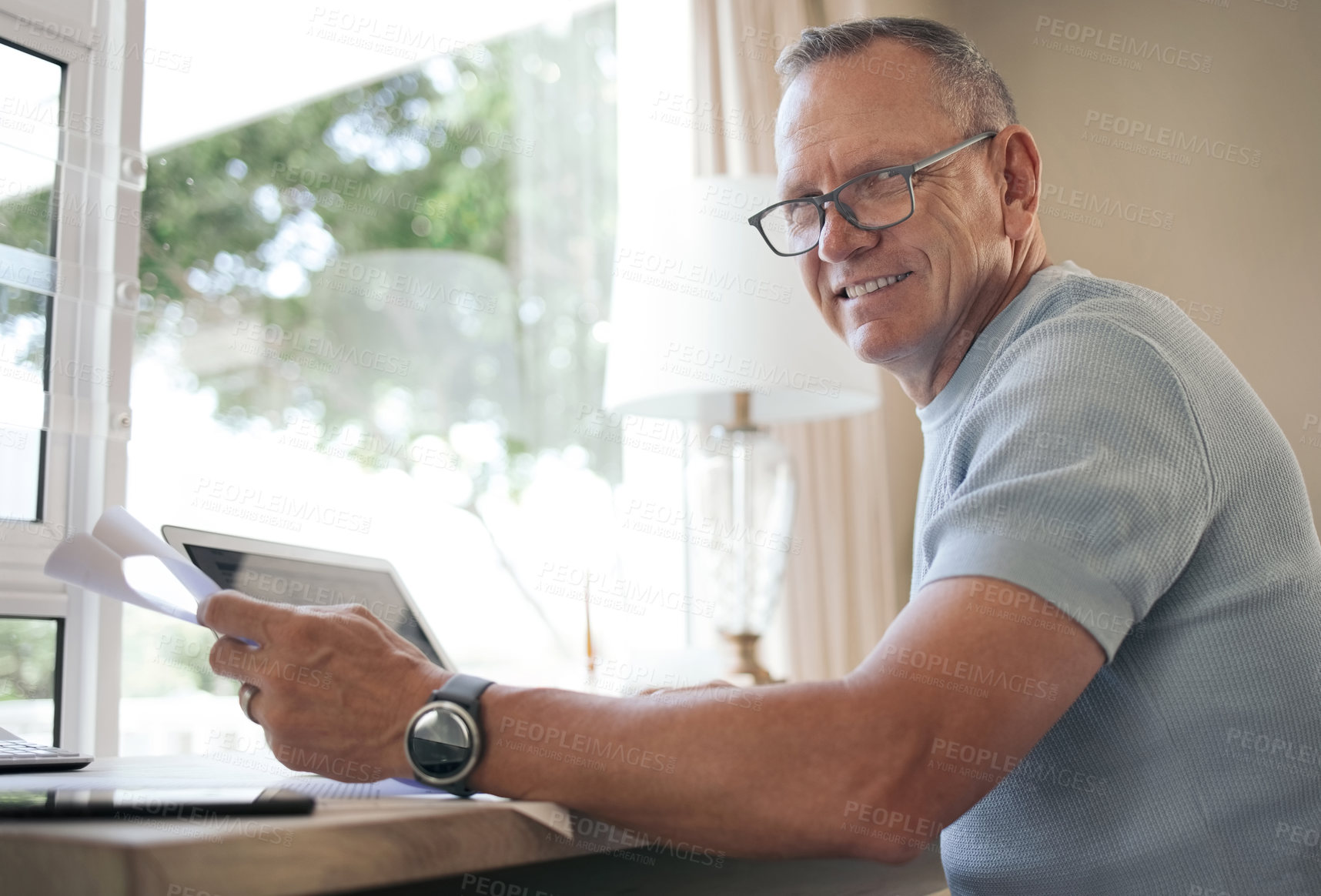 Buy stock photo Shot of a mature man reading over financial documents while working