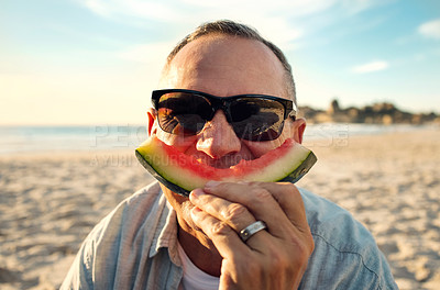Buy stock photo Shot of a mature man eating watermelon while at the beach