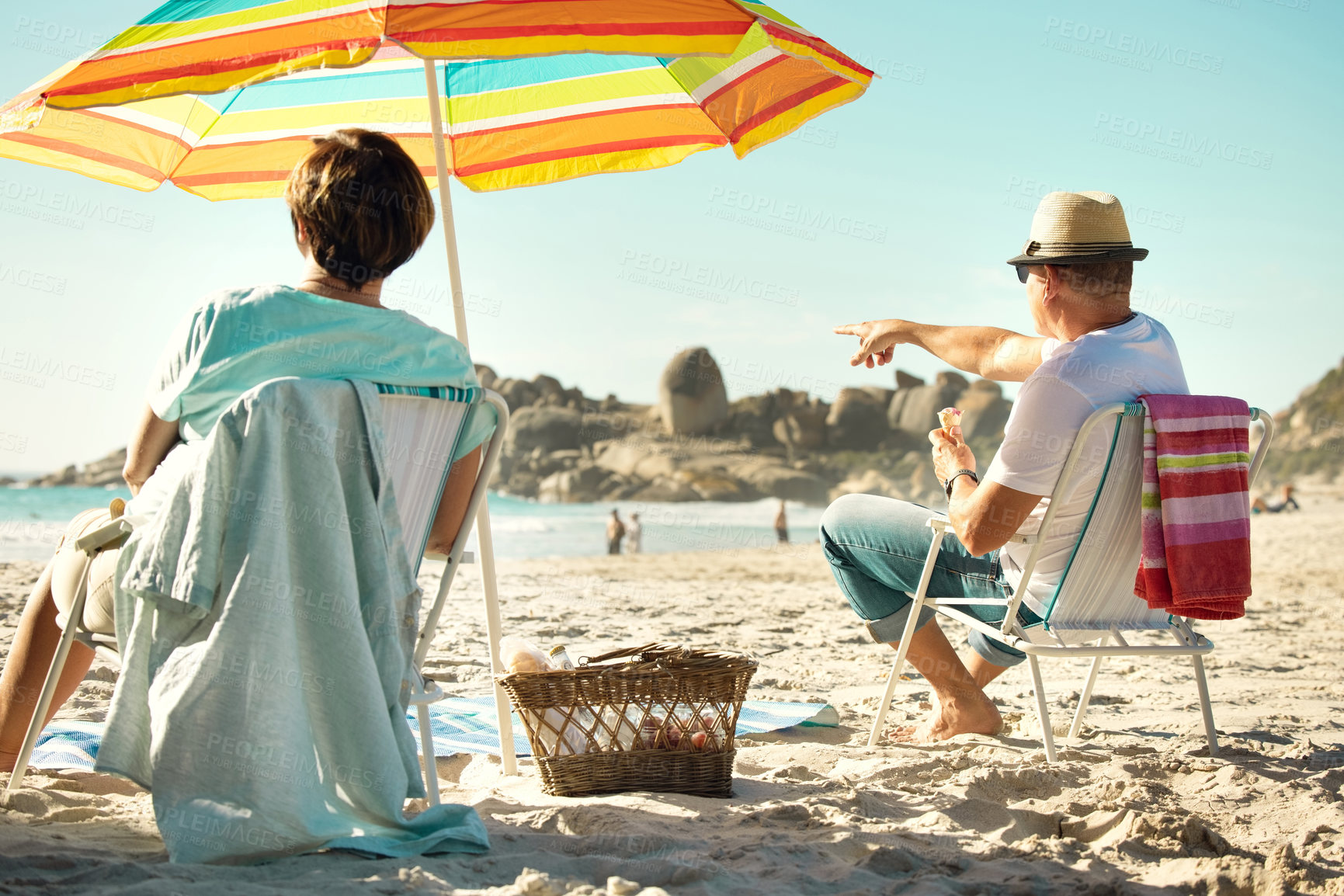 Buy stock photo Shot of a couple sitting on their chairs while enjoying a day at the beach