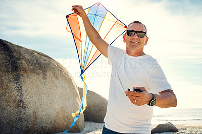 Buy stock photo Shot of a mature man holding a kite while at the beach