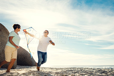 Buy stock photo Shot of a mature couple on the beach with a kite