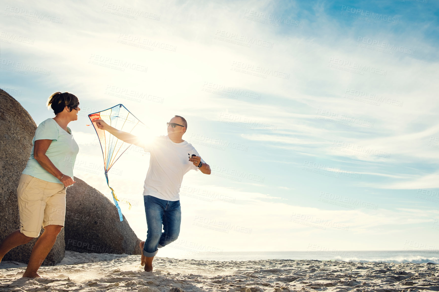 Buy stock photo Shot of a mature couple on the beach with a kite