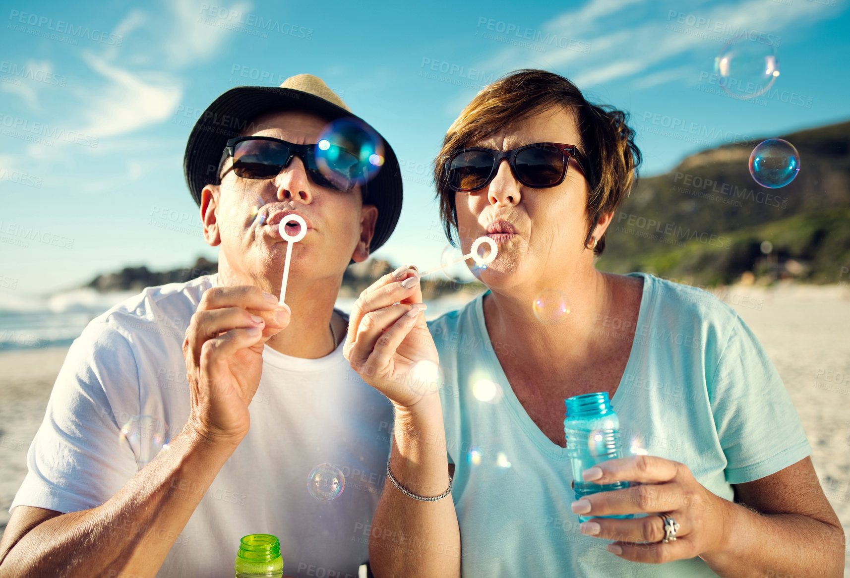 Buy stock photo Shot of a mature couple blowing bubbles together while at the beach