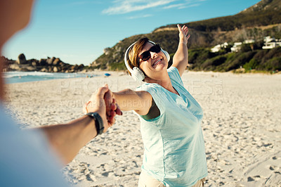 Buy stock photo Shot of a woman wearing headphones and enjoying herself at the beach