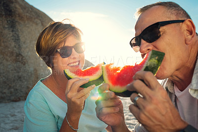 Buy stock photo Shot of a mature couple eating watermelon while at the beach