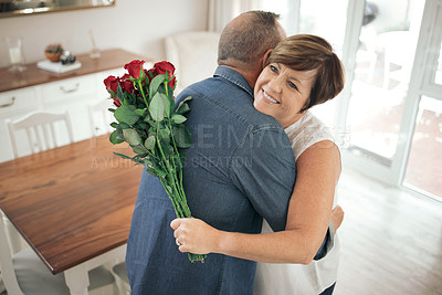 Buy stock photo Shot of a mature wife hugging her husband for the gift of roses