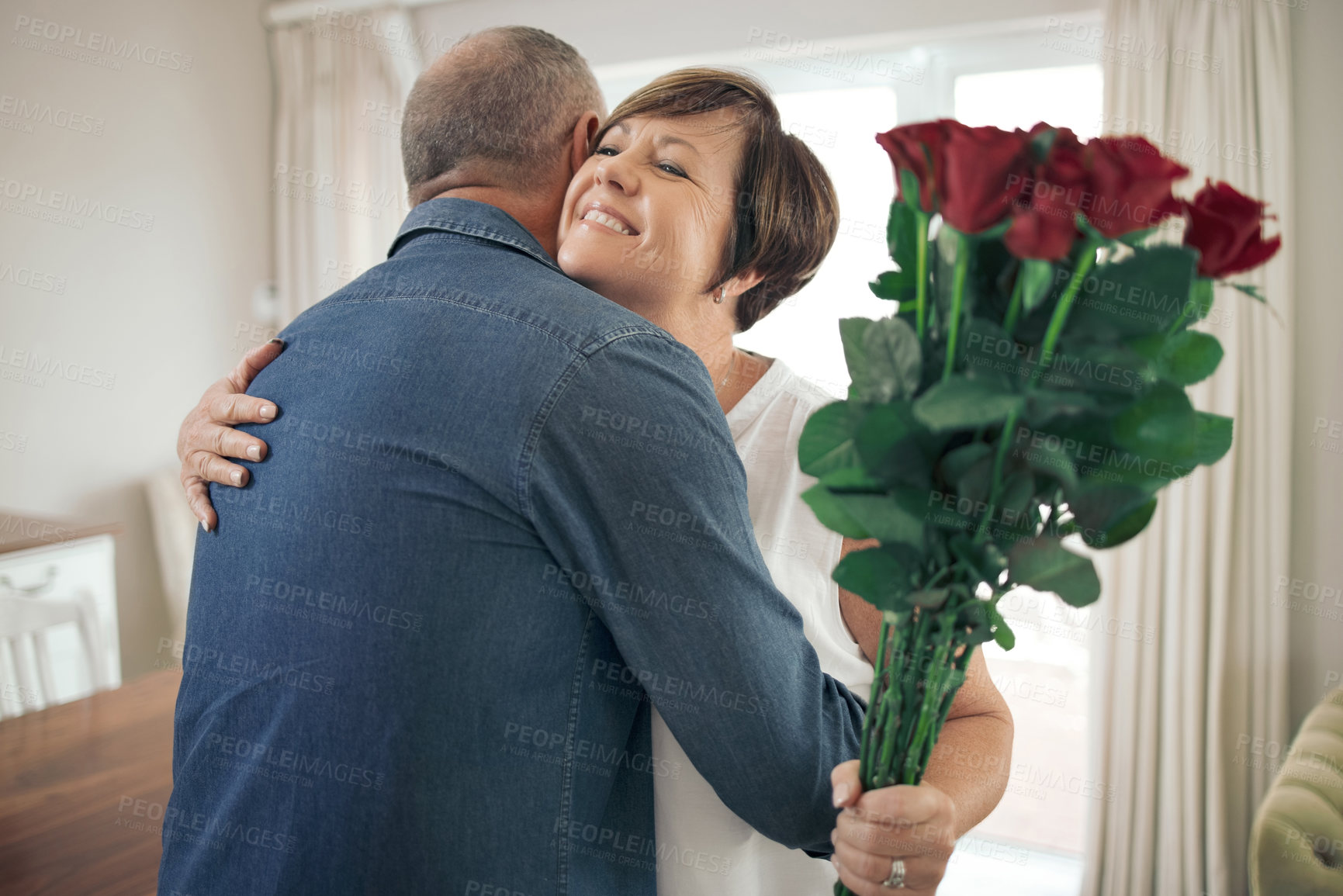 Buy stock photo Shot of a mature wife hugging her husband for the gift of roses