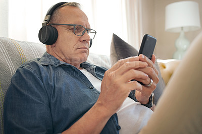 Buy stock photo Shot of a senior man using his smartphone to listen to music