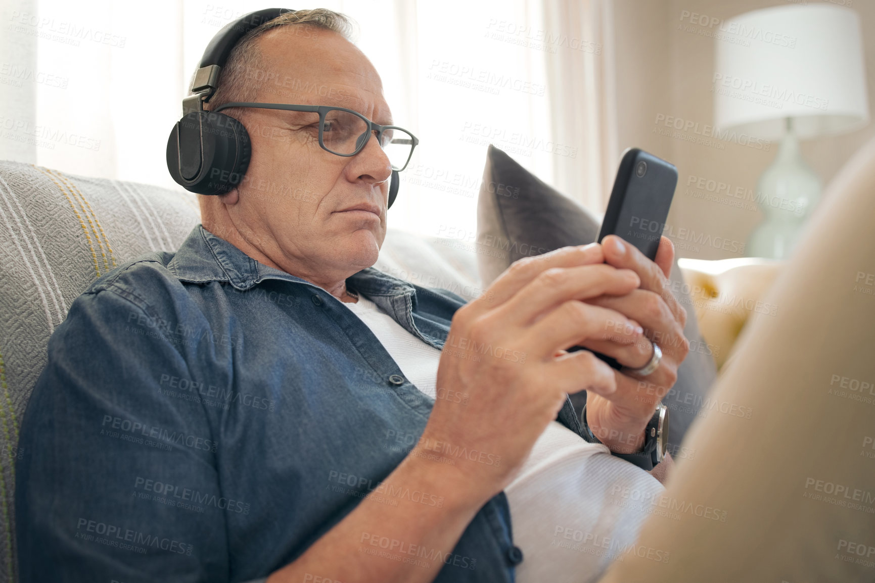 Buy stock photo Shot of a senior man using his smartphone to listen to music
