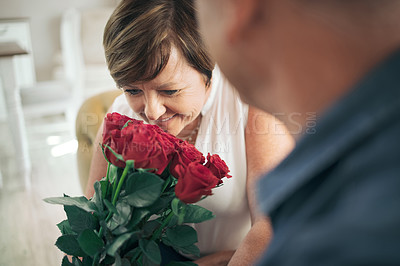 Buy stock photo Shot of a mature wife smelling the bouquet of roses her husband gave her