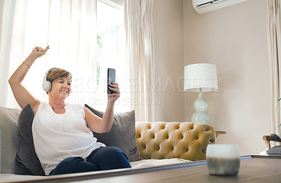 Buy stock photo Shot of a mature woman using her smartphone to take a selfie while listening to music