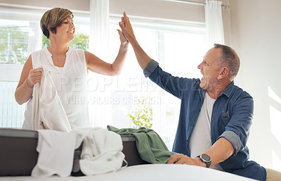 Buy stock photo Shot of a mature couple high fiving while folding their laundry