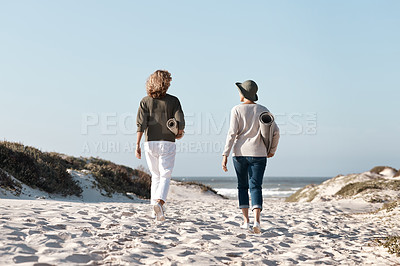 Buy stock photo Rearview shot of two unrecognizable woman walking with their mats on the beach