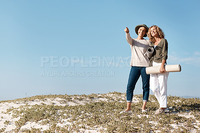 Buy stock photo Full length shot of two attractive mature woman standing with their on the beach